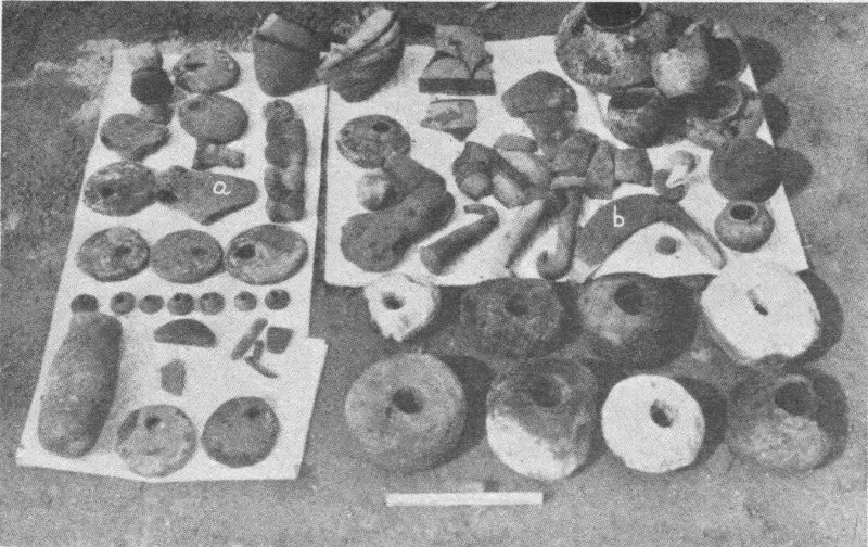 Black-and-white photo of assorted clay tokens and discs laid out on paper sheets, labeled “a” and “b”