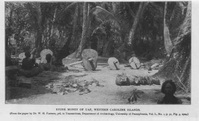 Old photo of Rai stone money discs lined up on a path among palm trees on Yap Island